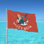 Flag with a shark and mermaid design against a blue ocean background