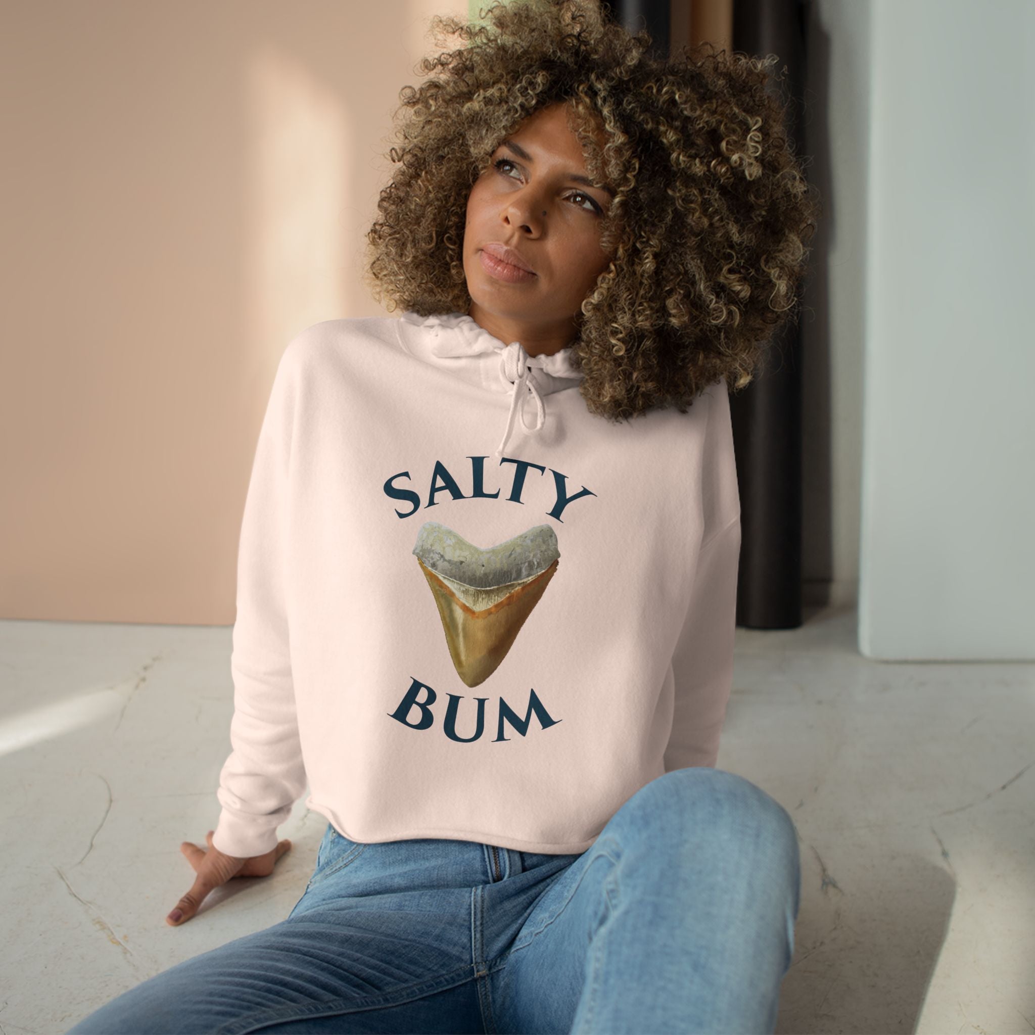 Person wearing a white hoodie with 'Salty Bum' graphic design sitting on a light-colored floor.