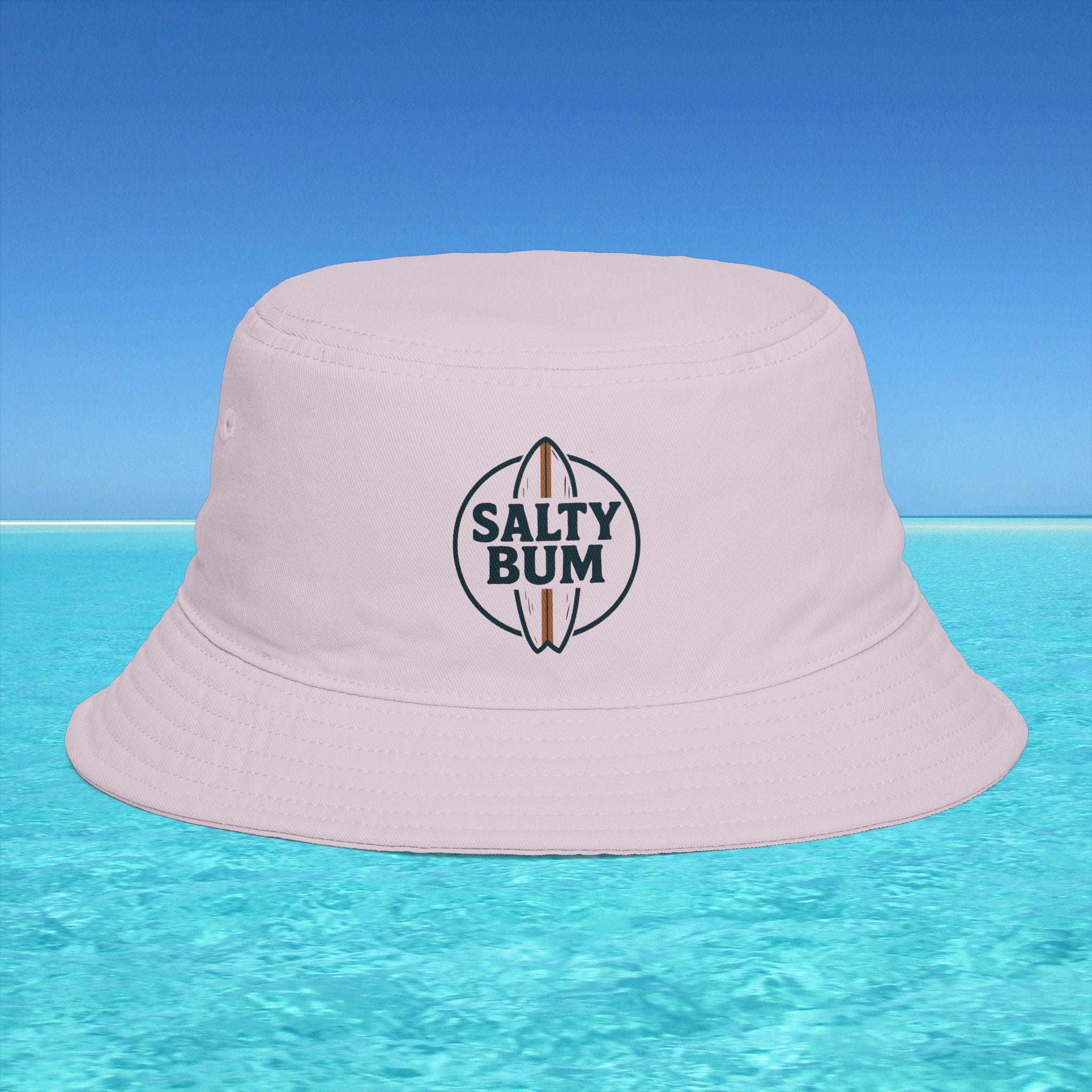 Pink bucket hat with 'Salty Bum' logo on a clear blue water background