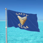 Flag with 'Salty Bum' text and a shark tooth graphic against a blue sky and ocean background.