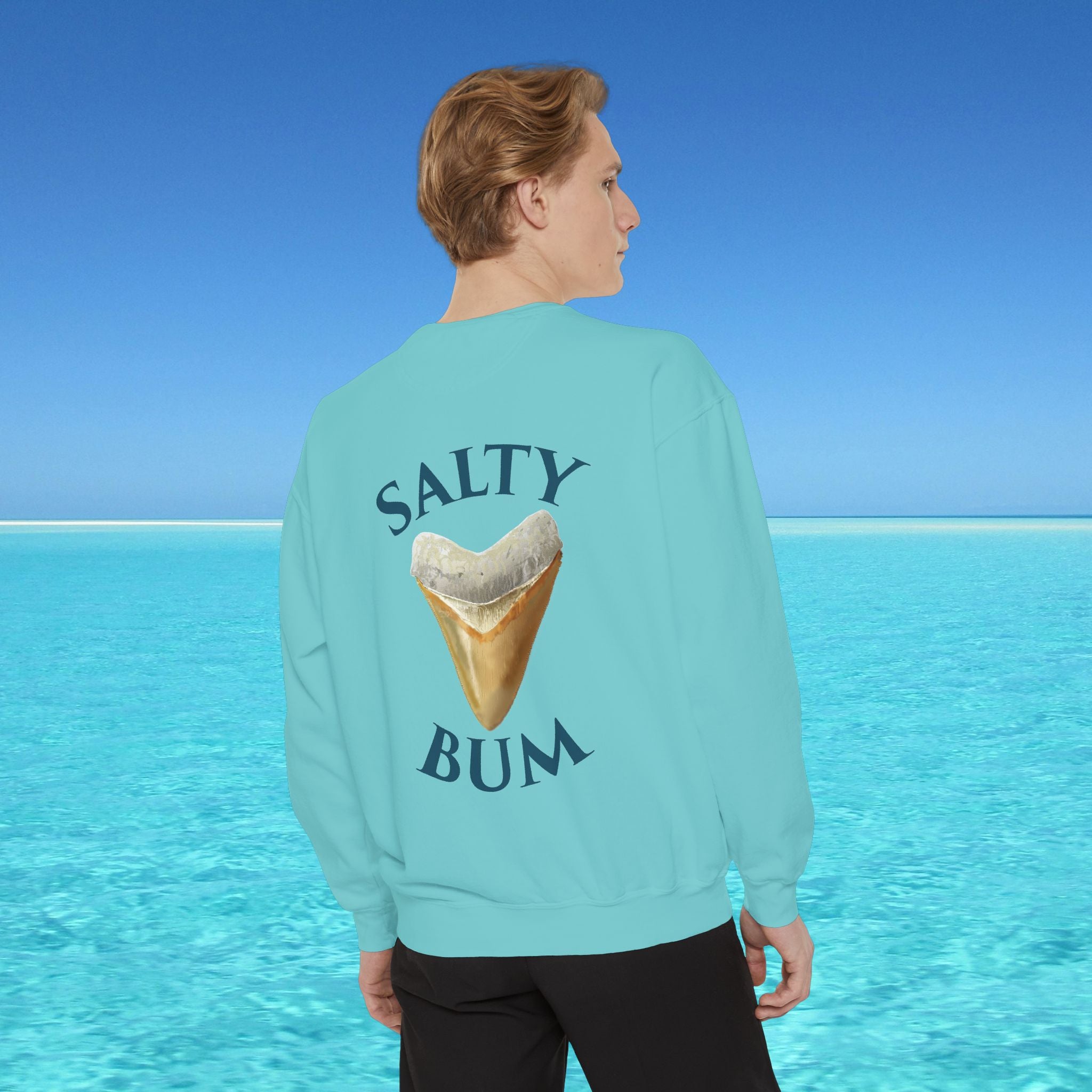 Person wearing a light blue sweatshirt with 'Salty Bum' text and an ice cream cone graphic, standing against a clear blue sky.