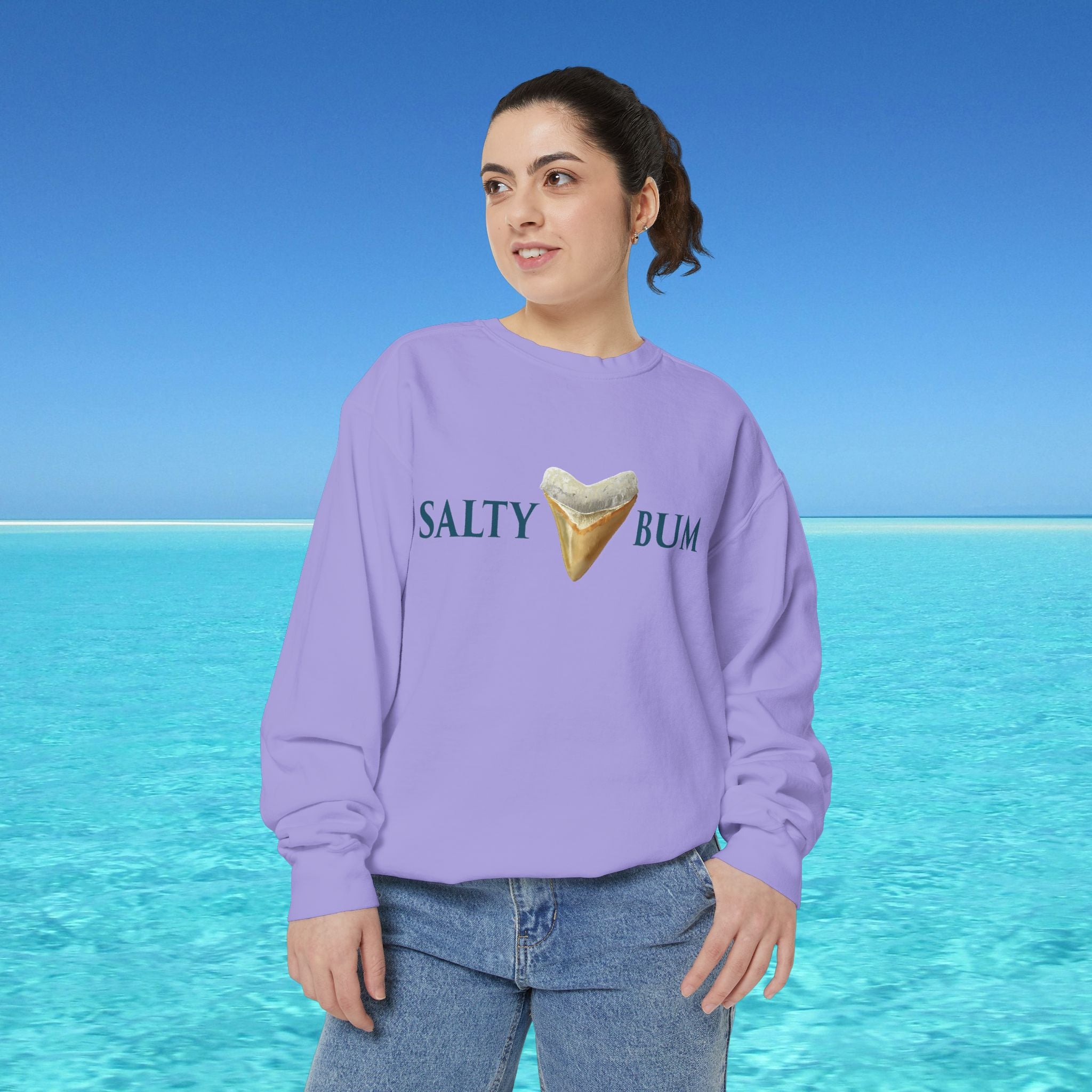 Person wearing a purple sweatshirt with 'Salty Bum' text and ice cream cone graphic against a blue ocean background