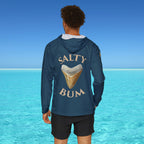 Person wearing a blue hoodie with 'Salty Bum' text and shark tooth graphic against a clear blue sky and ocean.