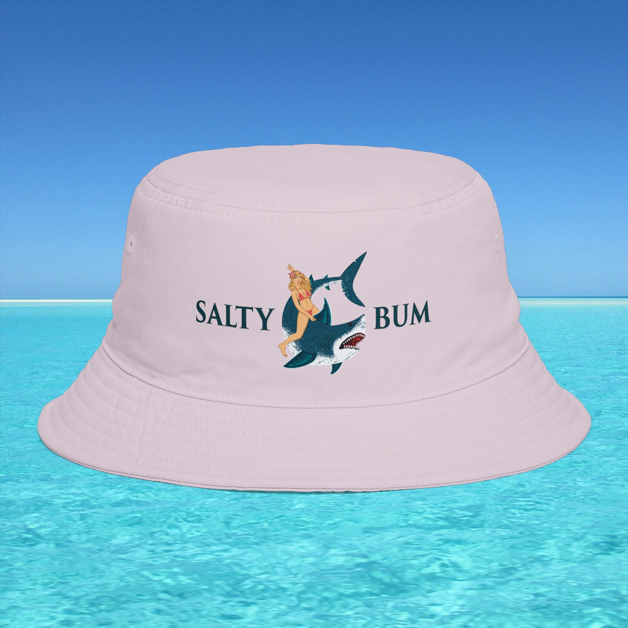 Pink bucket hat with 'Salty Bum' design on a blue water and sky background