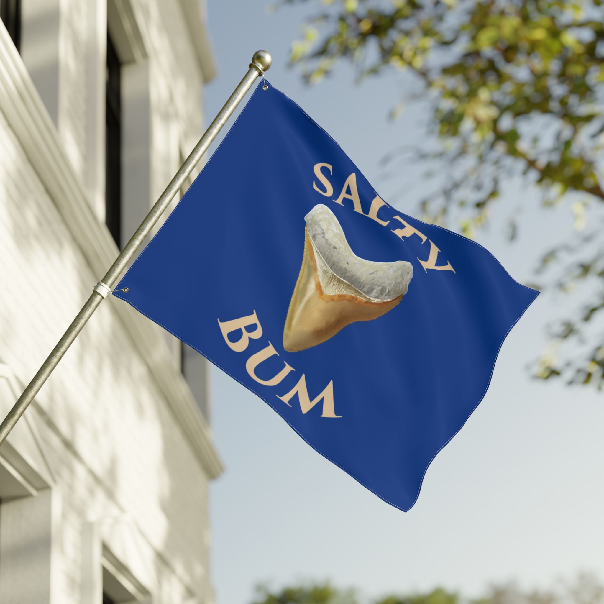 Flag with 'Salty Bum' text and a graphic of a corn dog against a blue background, waving in front of a building.
