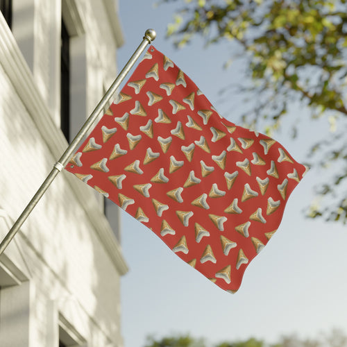 Red flag with gold and white pattern waving in front of a building