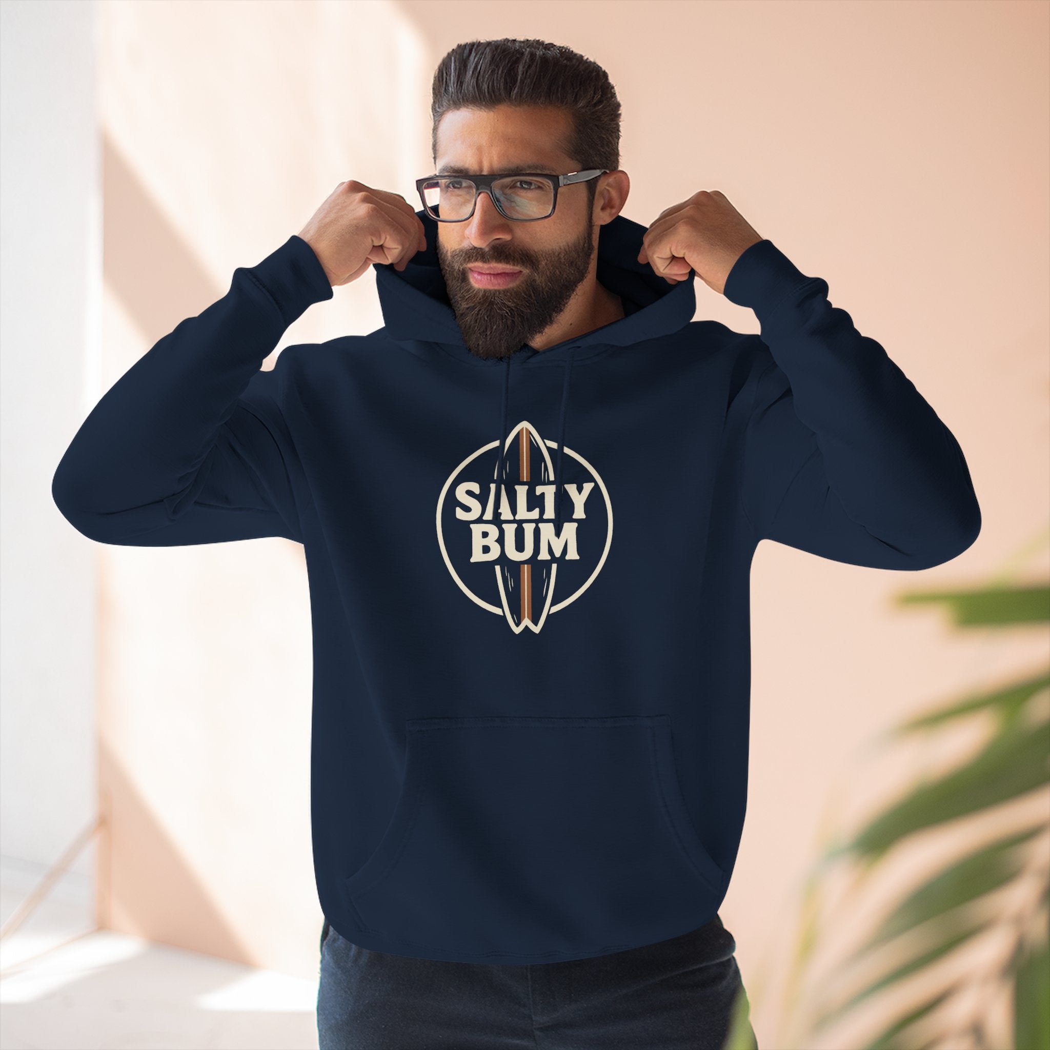 Man wearing a navy blue hoodie with 'Salty Bum' logo indoors.