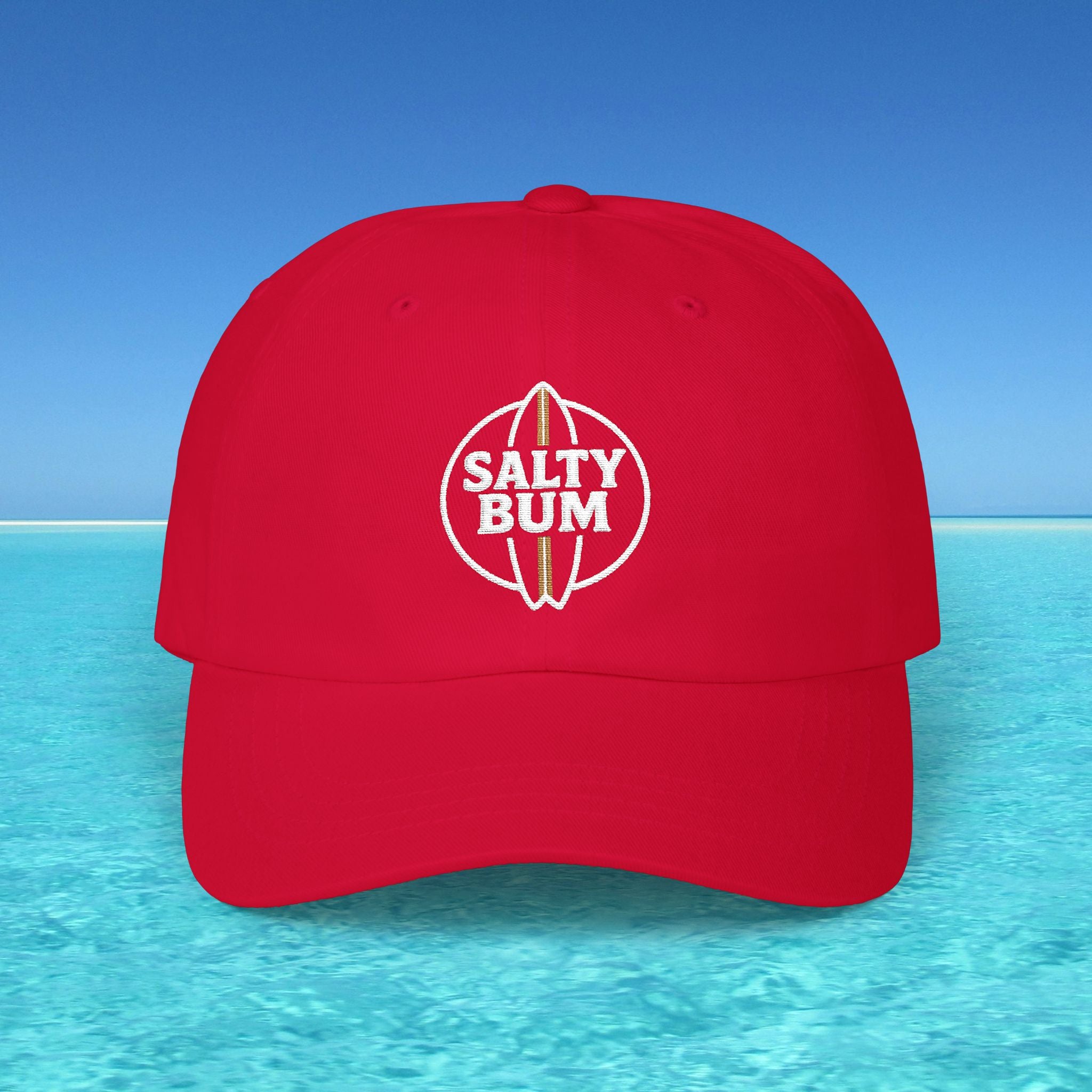 Red cap with 'Salty Bum' logo on a blue water and sky background