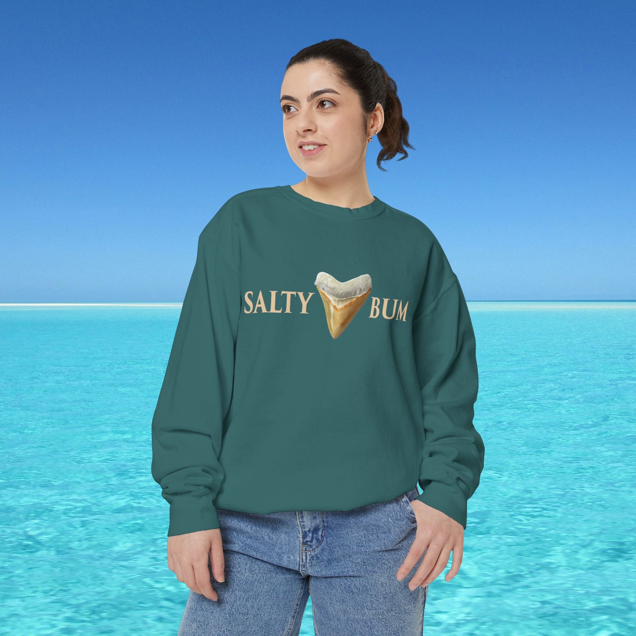 Person wearing a green sweatshirt with 'Salty Bum' text and ice cream graphic against a blue ocean background