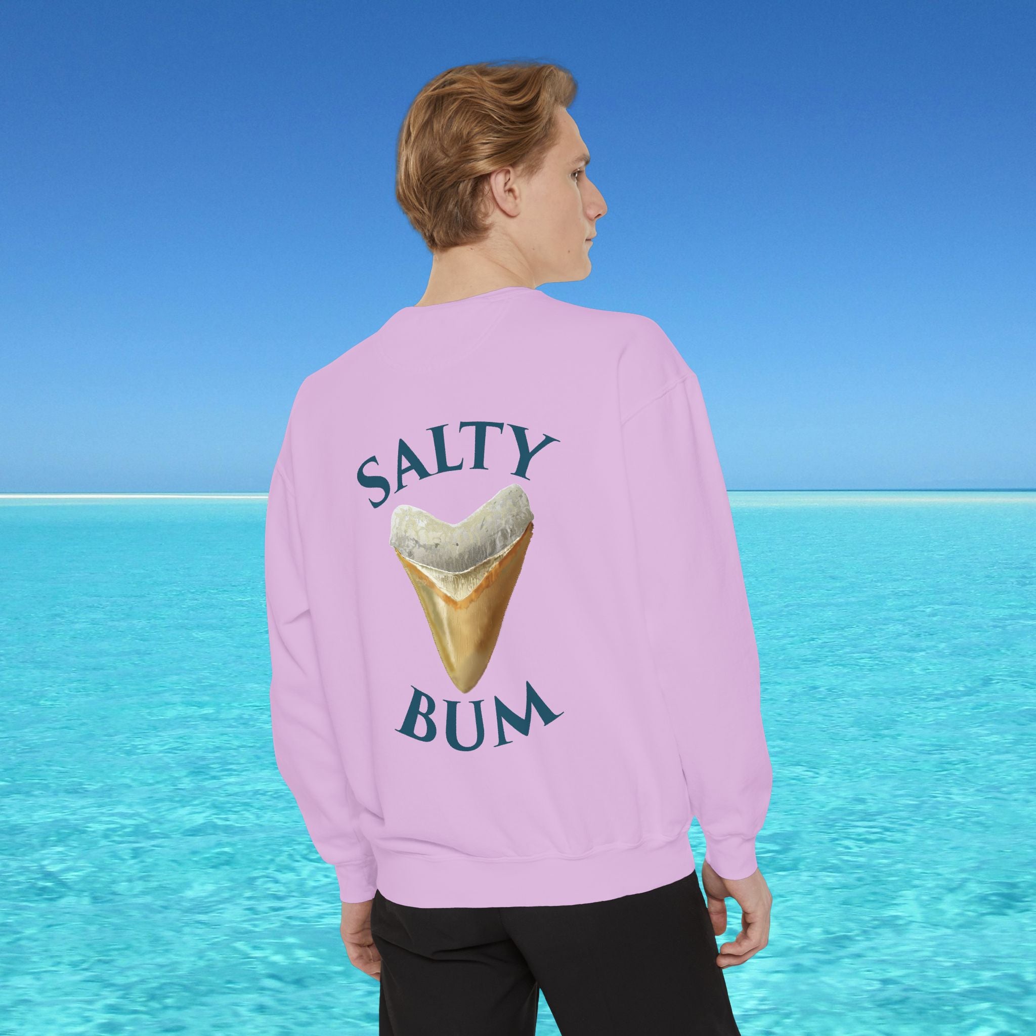 Person wearing a pink sweatshirt with 'Salty Bum' text and ice cream graphic, standing against a blue water and sky background.