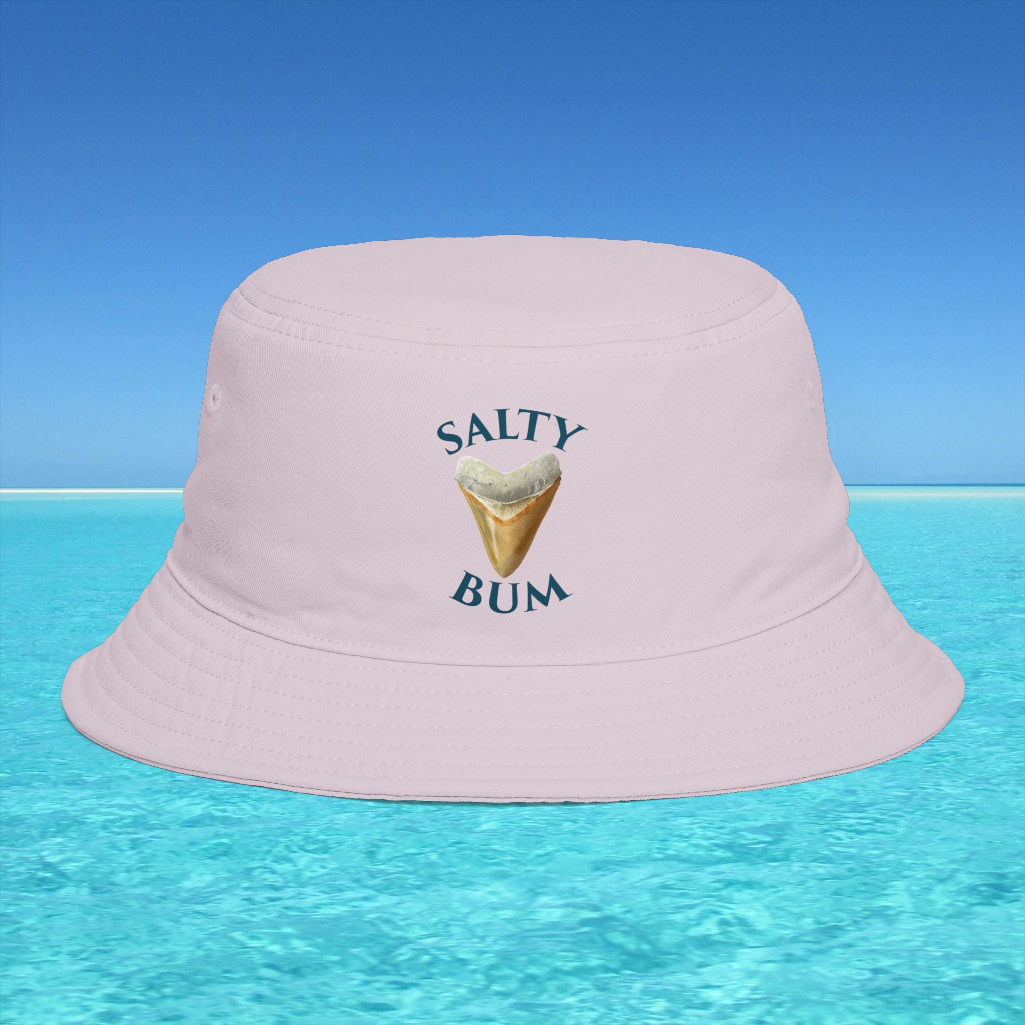 Pink bucket hat with 'Salty Bum' text and ice cream graphic on a blue water and sky background