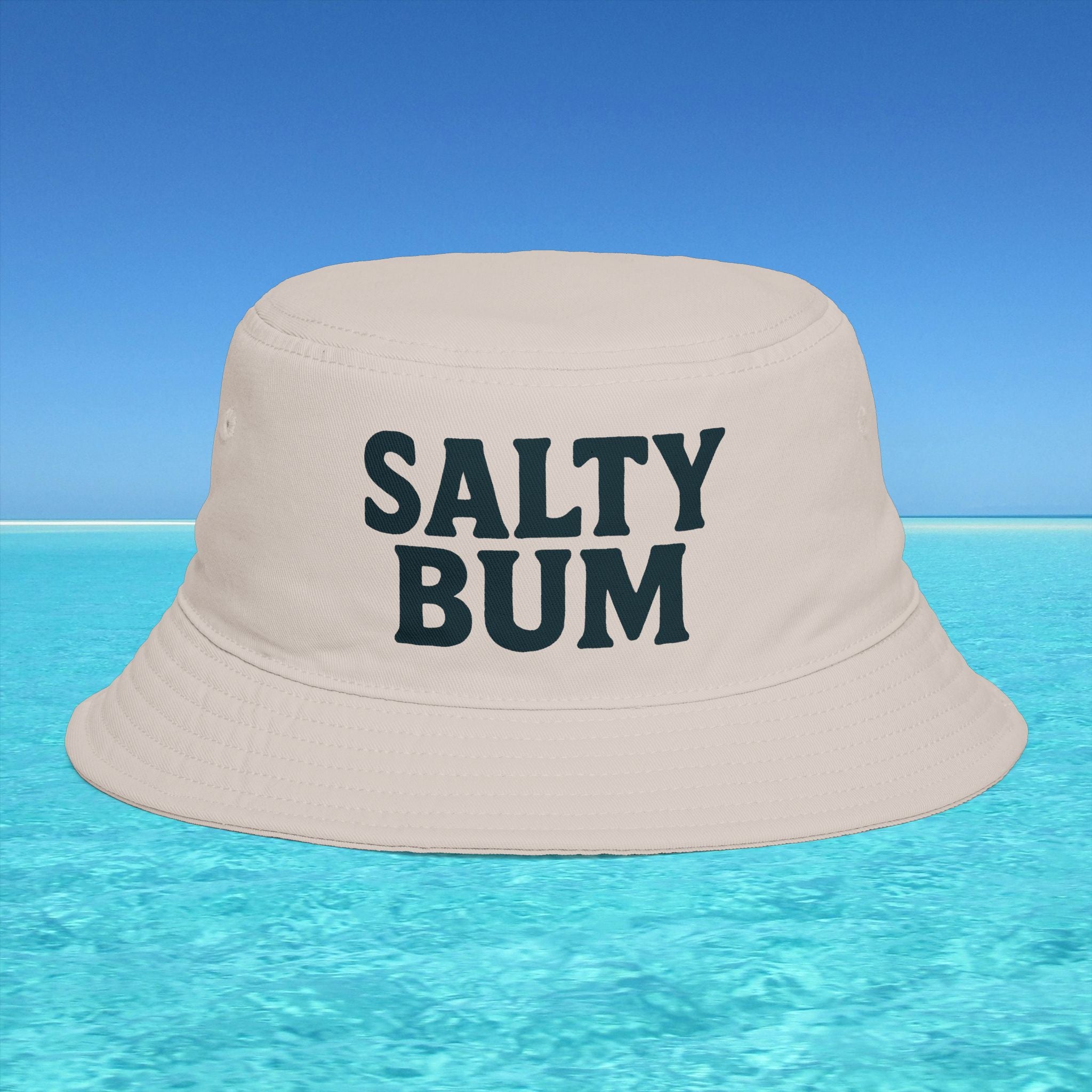 Beige bucket hat with 'Salty Bum' text on a blue water and sky background