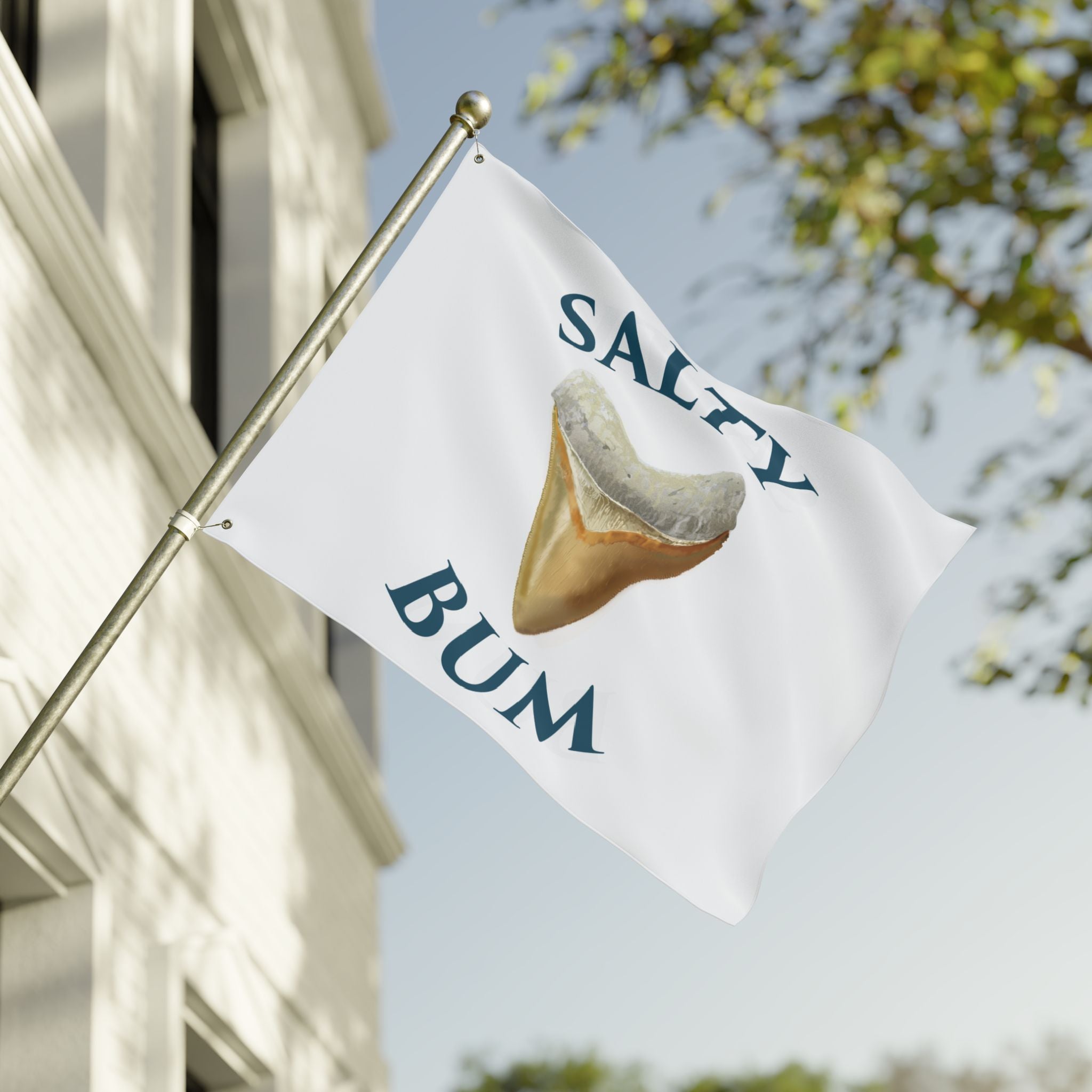 Flag with 'Salty Bum' text and a shark fin graphic waving in front of a building.