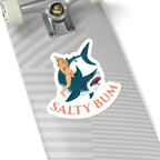 Skateboard with a 'Salty Bum' sticker featuring a shark and woman on a white background