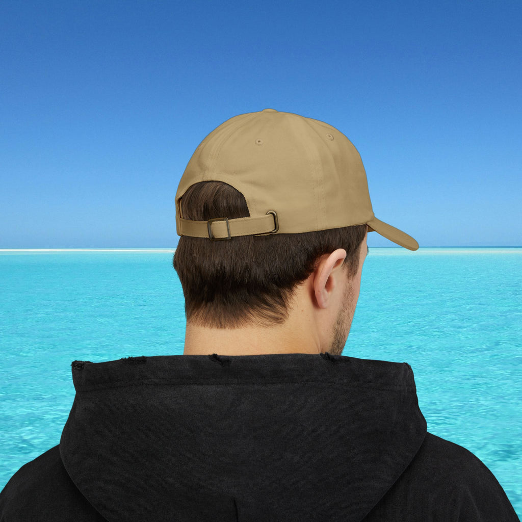 Person wearing a beige cap and black hoodie with a blue water and sky background
