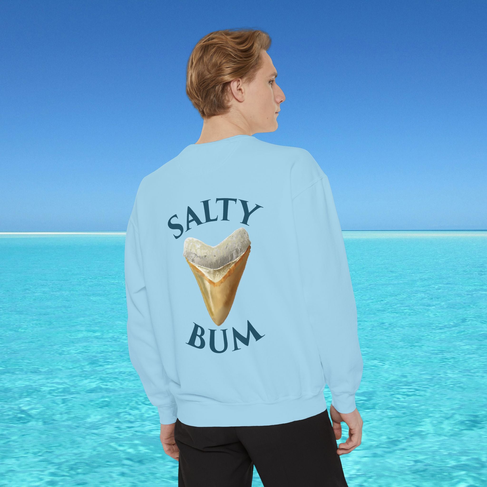 Person wearing a light blue sweatshirt with 'Salty Bum' text and a graphic of a sand dollar against a clear blue ocean background.