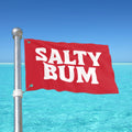 Red flag with 'Salty Bum' text against a clear blue sky and ocean.