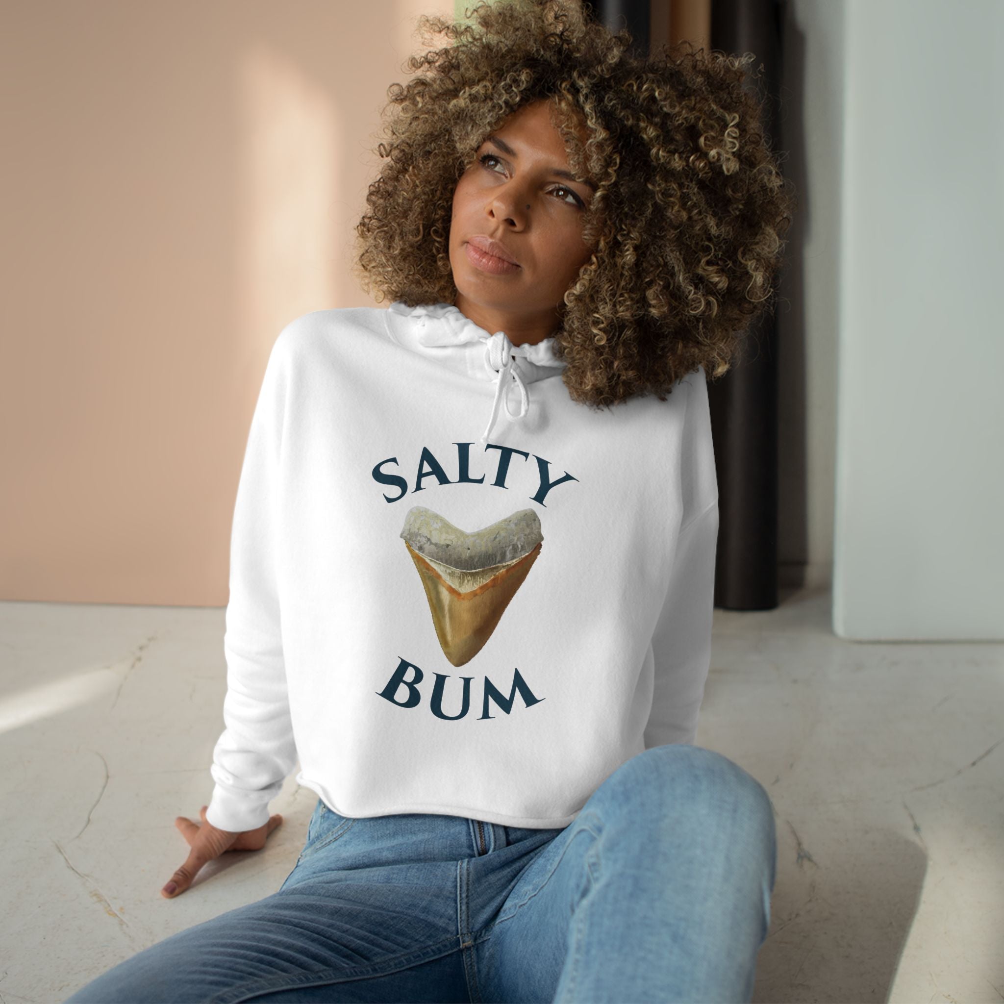 Person wearing a white hoodie with 'Salty Bum' text and graphic, sitting indoors.