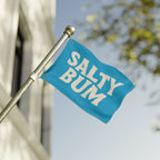 Blue flag with 'Salty Bum' text on a pole against a blurred background