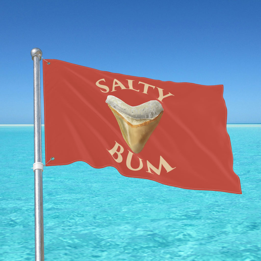 Red flag with 'Salty Bum' text and a shark tooth graphic against a blue ocean and sky background