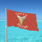 Red flag with 'Salty Bum' text and a shark tooth graphic against a blue ocean and sky background