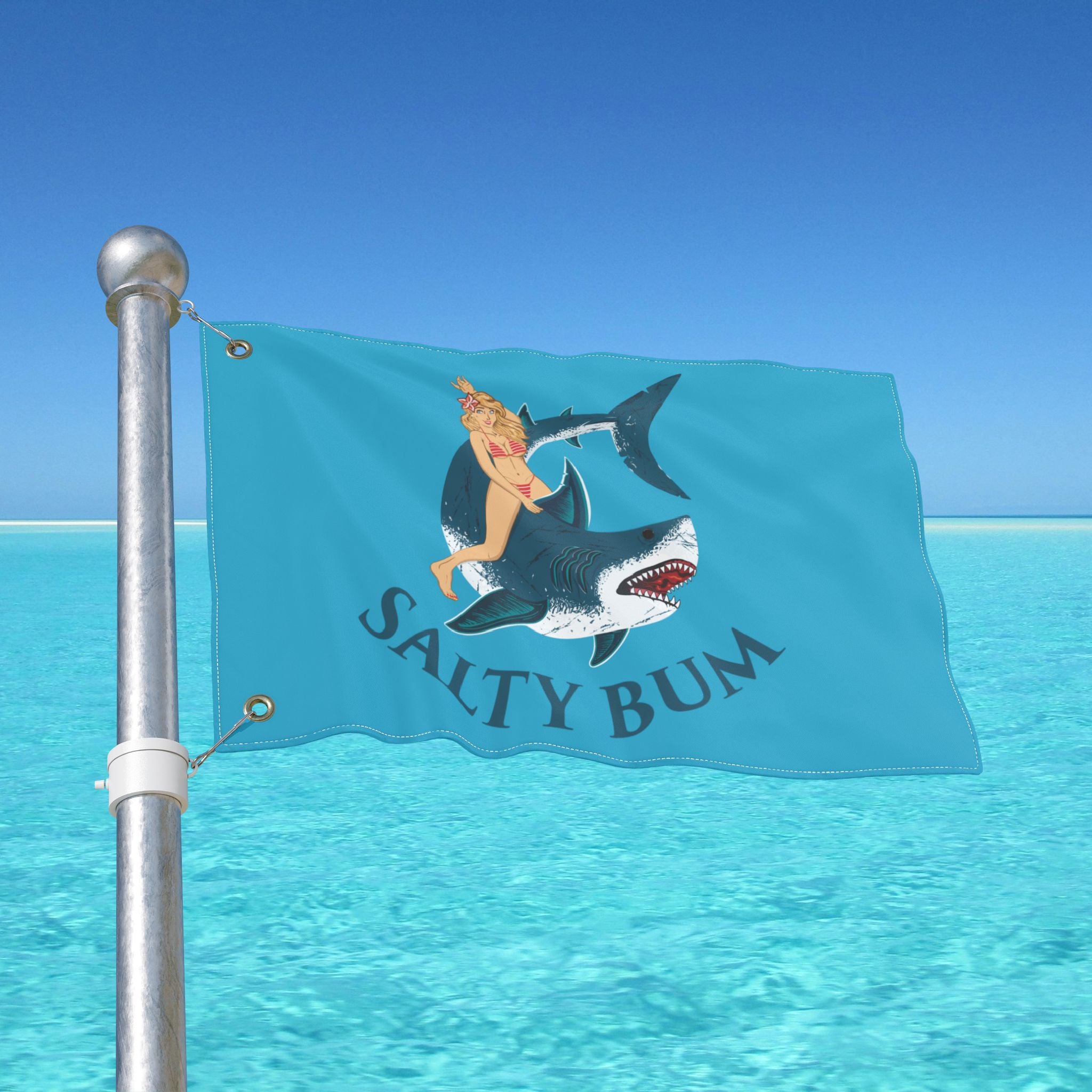 Flag with a graphic of a person on a shark and 'Salty Bum' text, against a clear blue sky.