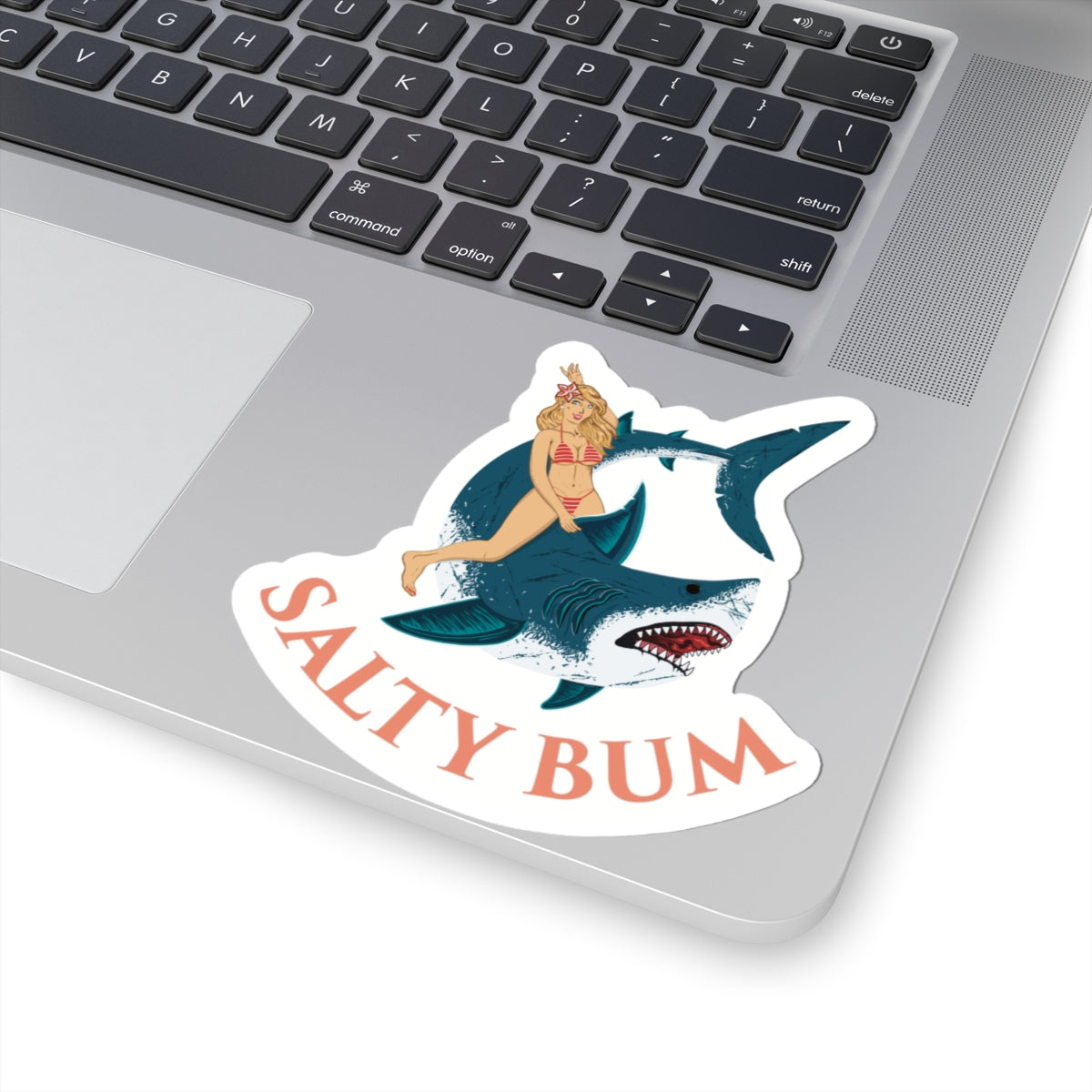 Sticker with a shark and woman design labeled 'Salty Bum' on a laptop.