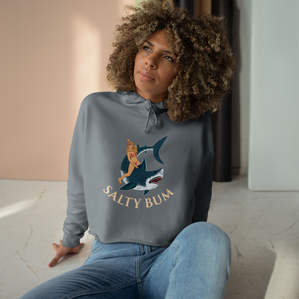 Woman wearing a gray sweatshirt with a graphic design and text, sitting indoors.