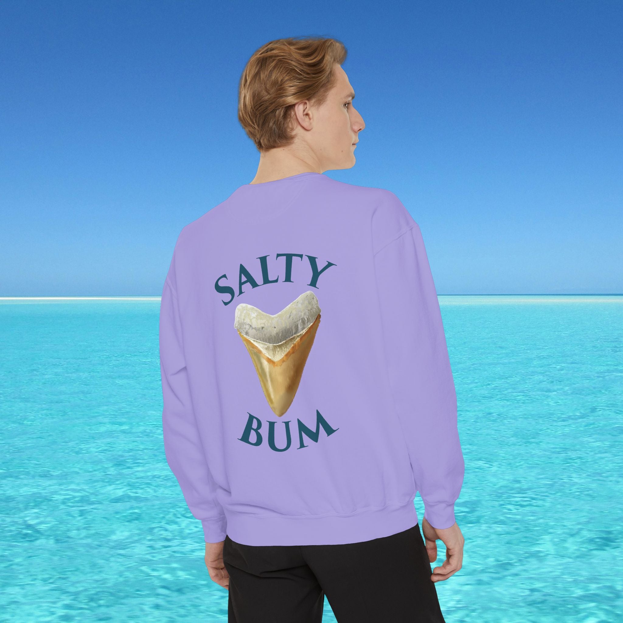 Person wearing a purple sweatshirt with 'Salty Bum' text and ice cream graphic, standing against a blue water and sky background.