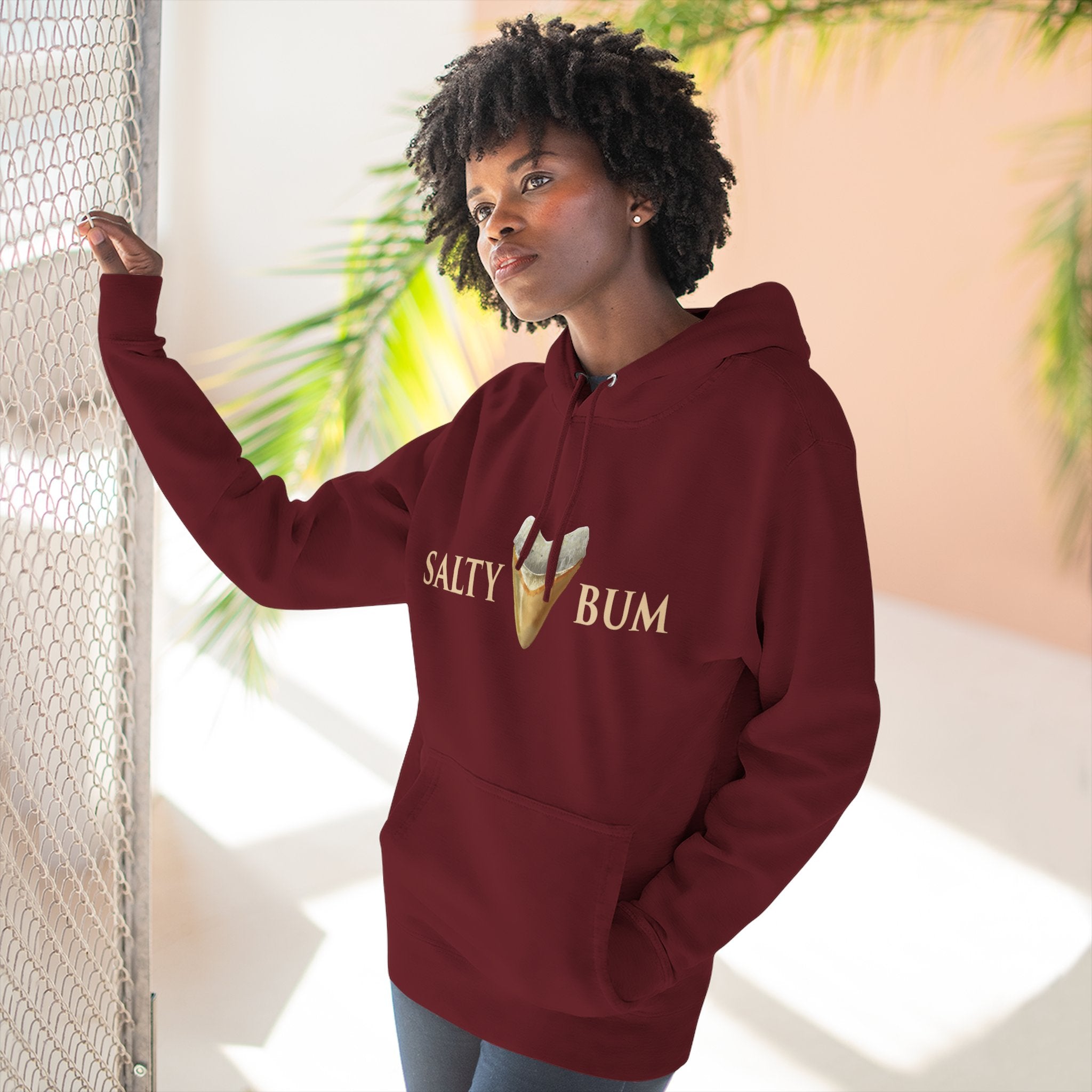 Woman wearing a maroon hoodie with 'Salty Bum' text and ice cream graphic, standing indoors.